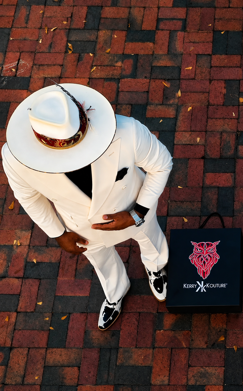 Overhead shot of Kerry in an ivory suit and white wide-brim fedora beside the Kerry Kouture shopping bag