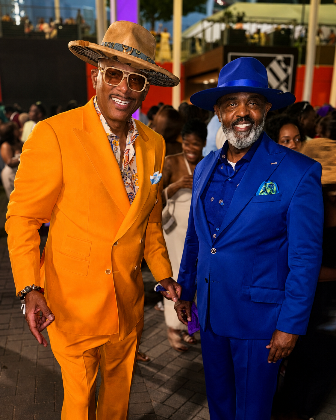 Kerry in a marigold suit and tan fedora beside a client in cobalt blue with a matching fedora
